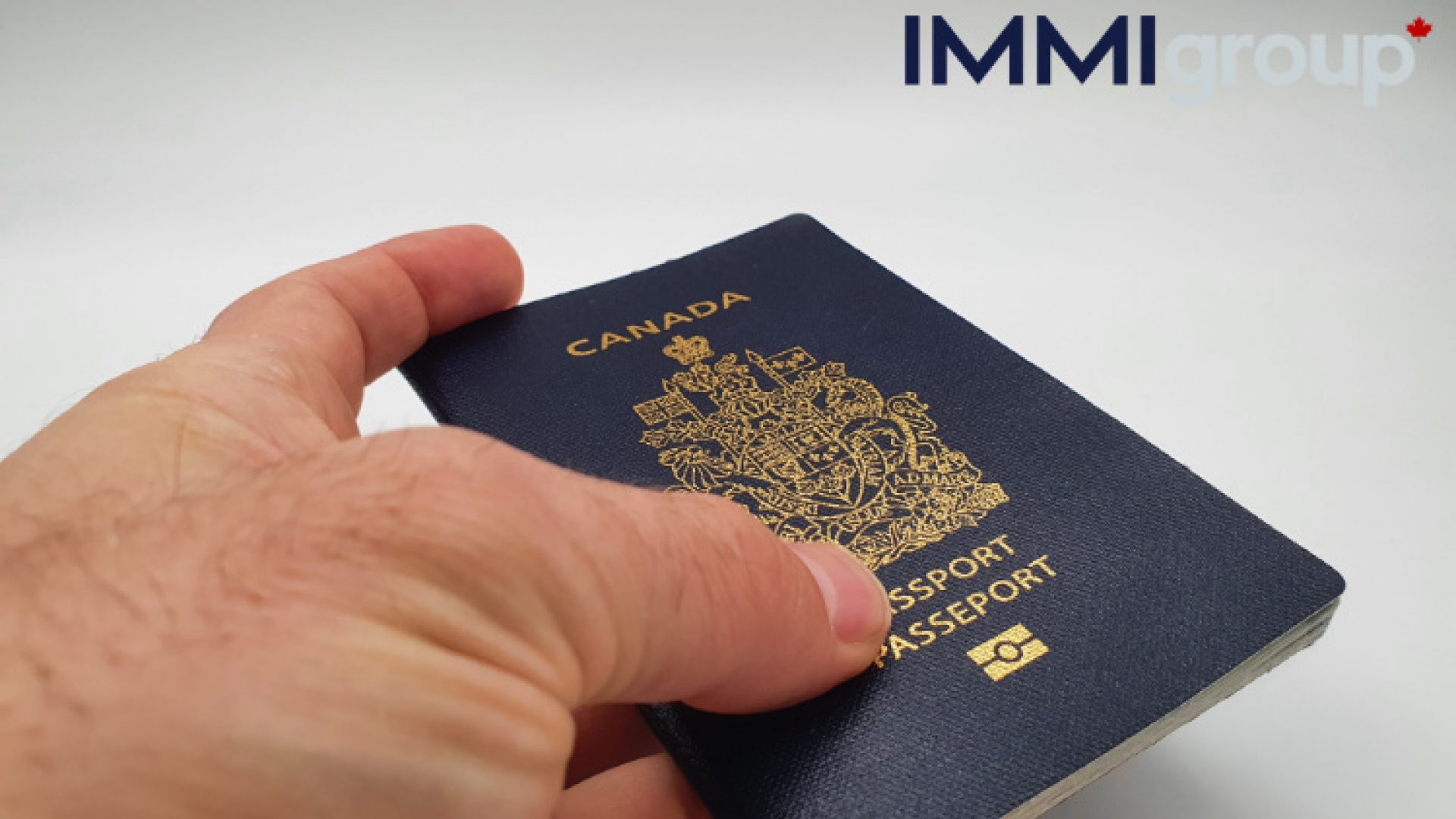 shows a hand holding a Canadian passport. It the fist passport from Canada.